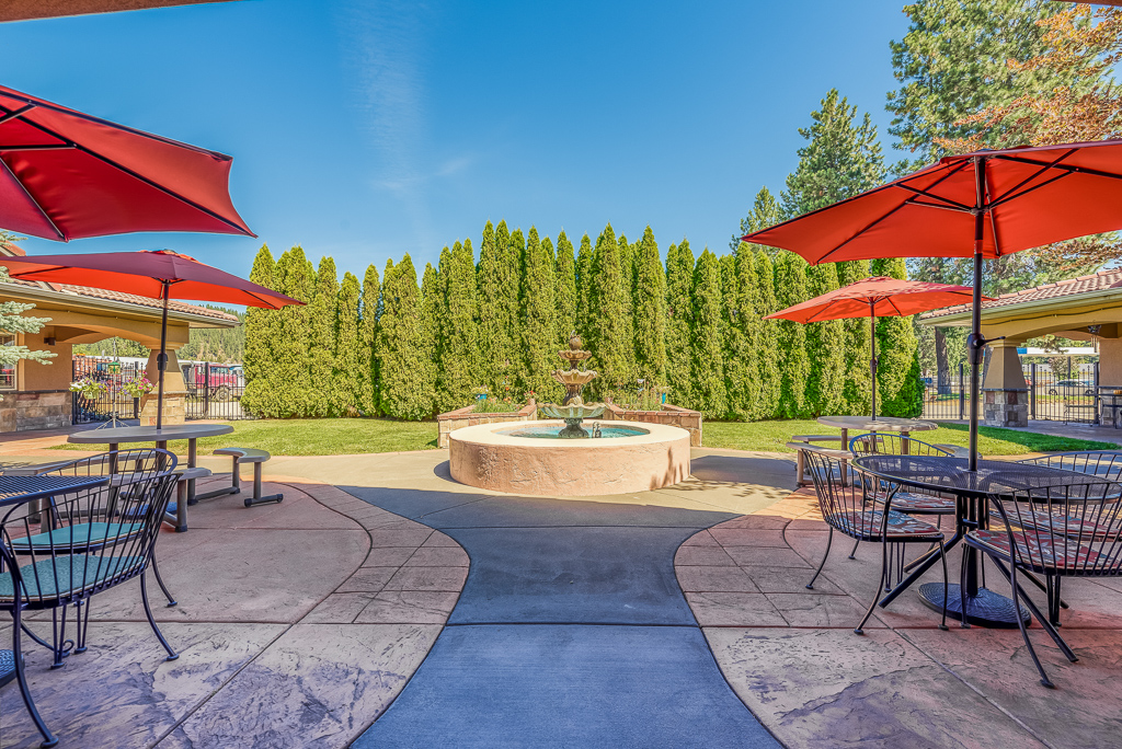 courtyard surrounded by trees with red umbrellas over seating